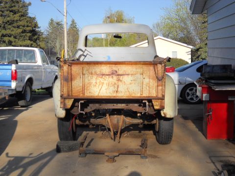 1954 Ford F-100 - Rear view of a weathered 1953 Ford F-100 truck, showing its aged tailgate and chassis.
