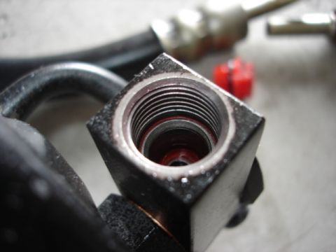 1992 Ford Bronco - Hydraulic fitting detail with a red cap in the background.