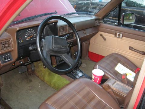 1987 Toyota 4Runner - The interior of a 1987 Toyota 4Runner features plaid seats, a Toyota steering wheel, and a dashboard with a prominent tachometer.
