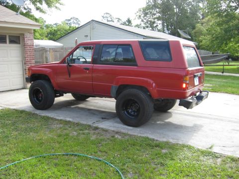 1987 Toyota 4Runner - This red 1987 Toyota 4Runner is parked on a concrete driveway in front of a brick garage.