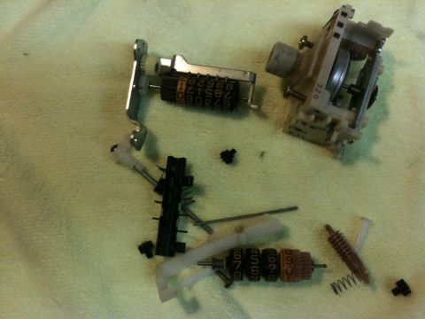 Suzuki Samurai - Disassembled odometer mechanism laid out on a yellow towel, showing two number-wheel drums (one reading 210789... in white, another reading…