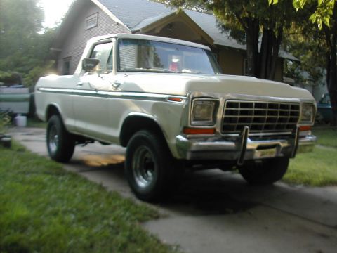 1979 Ford Bronco - A white Ford Bronco from the late 1970s is parked in front of a house.