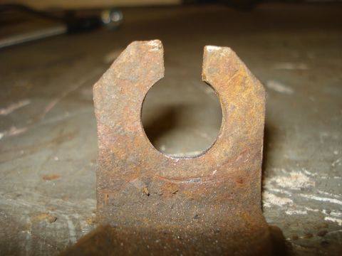 1979 Ford Bronco - Macro shot of a rusty stamped-steel brake hose bracket on a steel bench, its opening filed into a wider slotted keyhole with bright bare me…