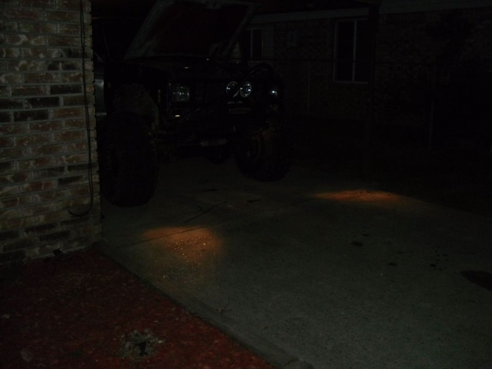 Black 1984 Ford Bronco II with hood open, parked in a driveway at night