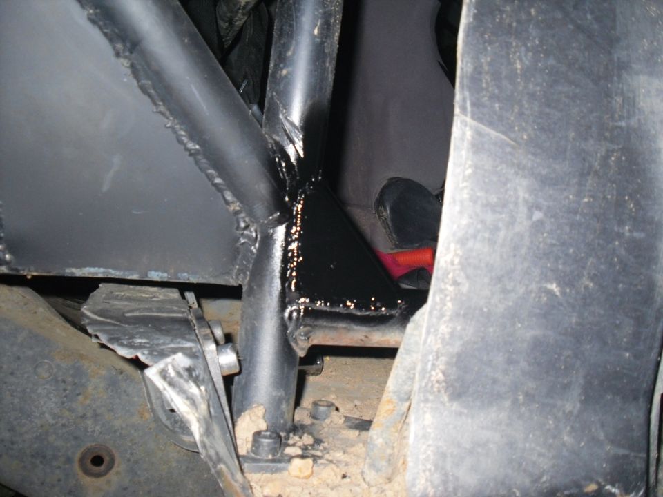 Modified black metal frame with visible welds and bolts, part of a vehicle's undercarriage