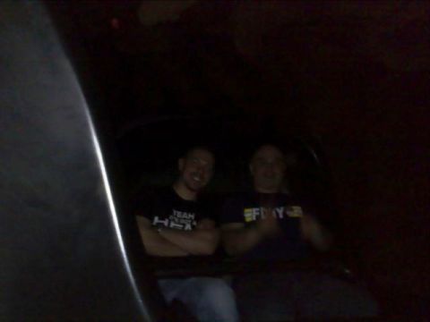 1991 Ford Crown Victoria - Two men are inside a car, one wearing a shirt with text. The year is not discernible.