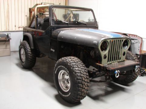1979 Jeep CJ7 - This Jeep CJ, likely from the mid-to-late 1970s, is undergoing modifications with a custom bumper and off-road tires.