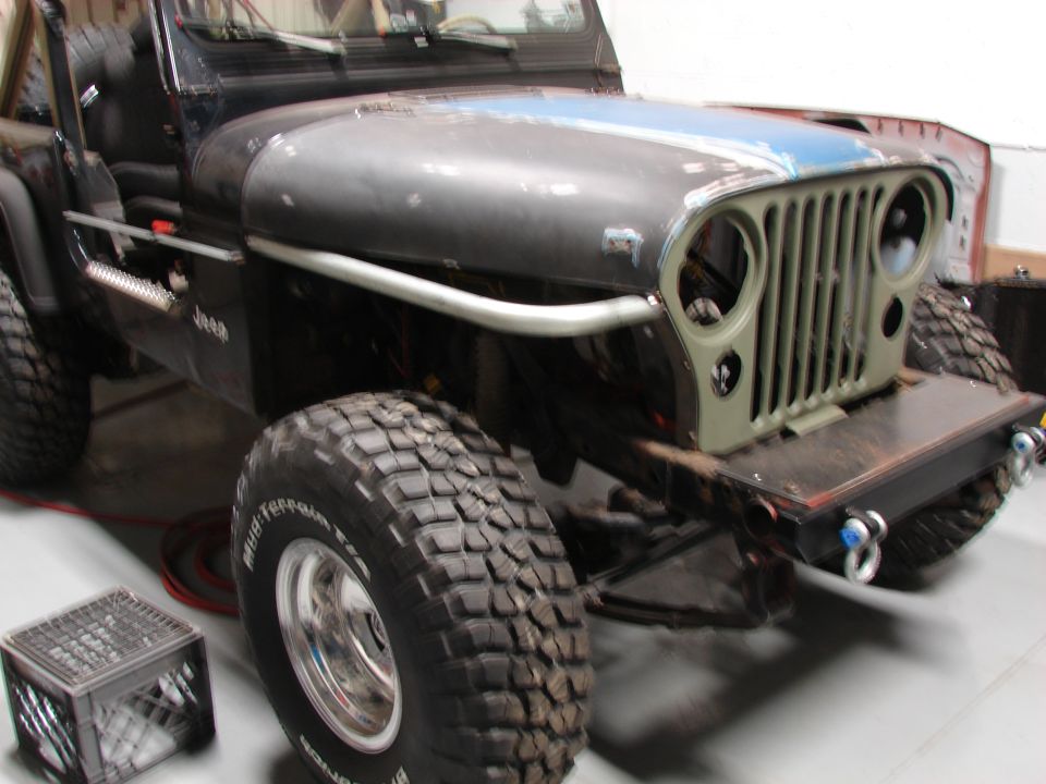 Jeep CJ-series front end with grille removed, showing off-road tires and custom bumper