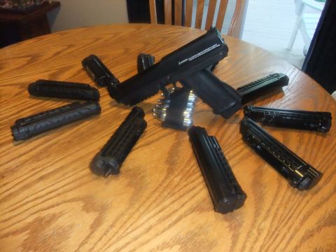 1978 Chevrolet C/K Pickup - An airsoft gun and its magazines are arranged on a round wooden table.