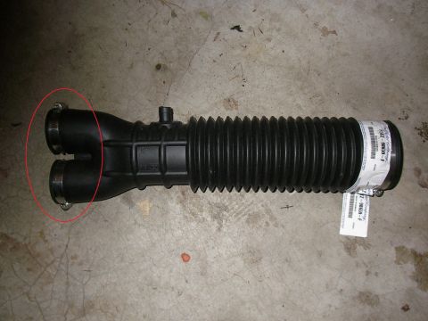 1990 Ford Bronco - A black rubber and plastic air intake tube with a flexible accordion-style bellows section, twin round outlet ports (circled in red) with m…