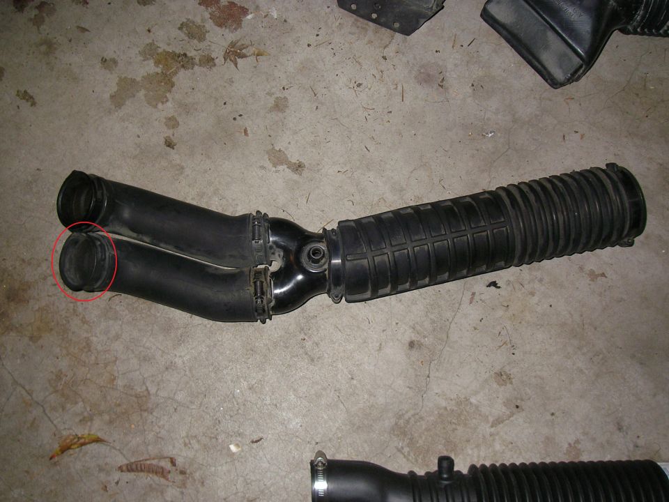 Black rubber air intake duct with accordion section lying on a concrete floor