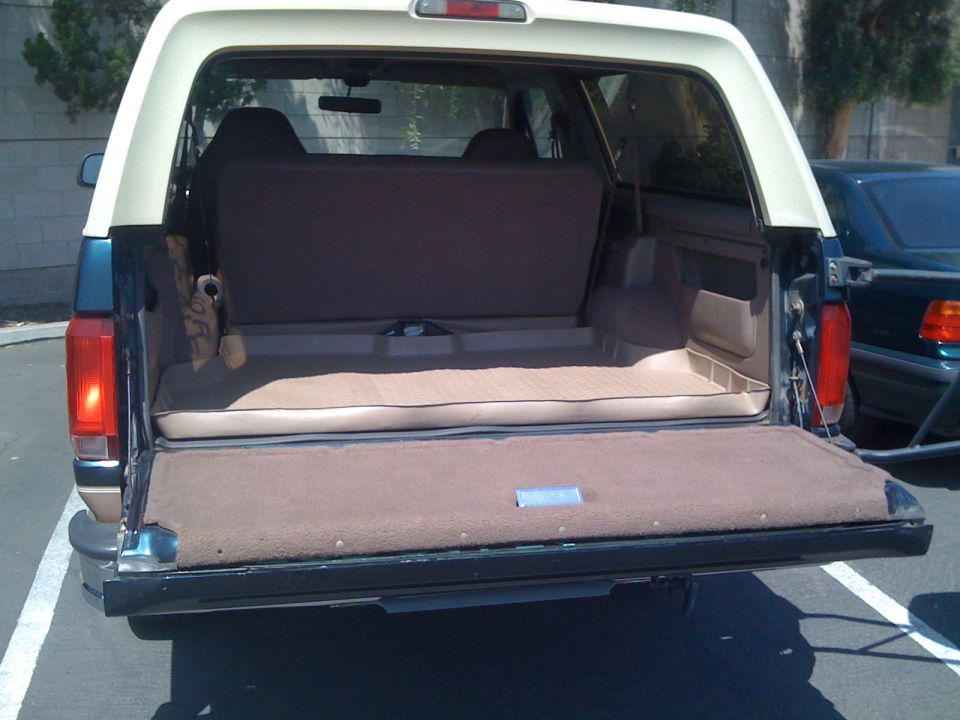 1995 Ford Bronco rear cargo area with seats folded down. Another vehicle is parked to the right