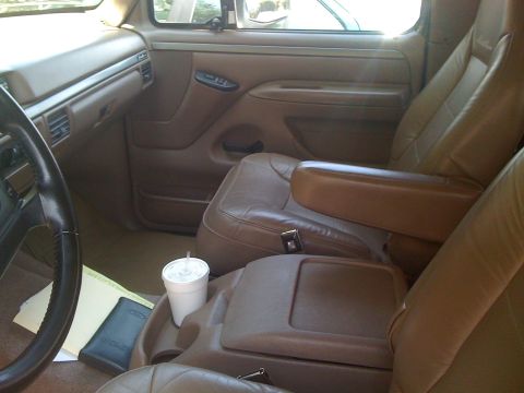 1995 Ford Bronco - The interior of this 1995 Ford Bronco features tan leather seats and a center console with a cup holder.