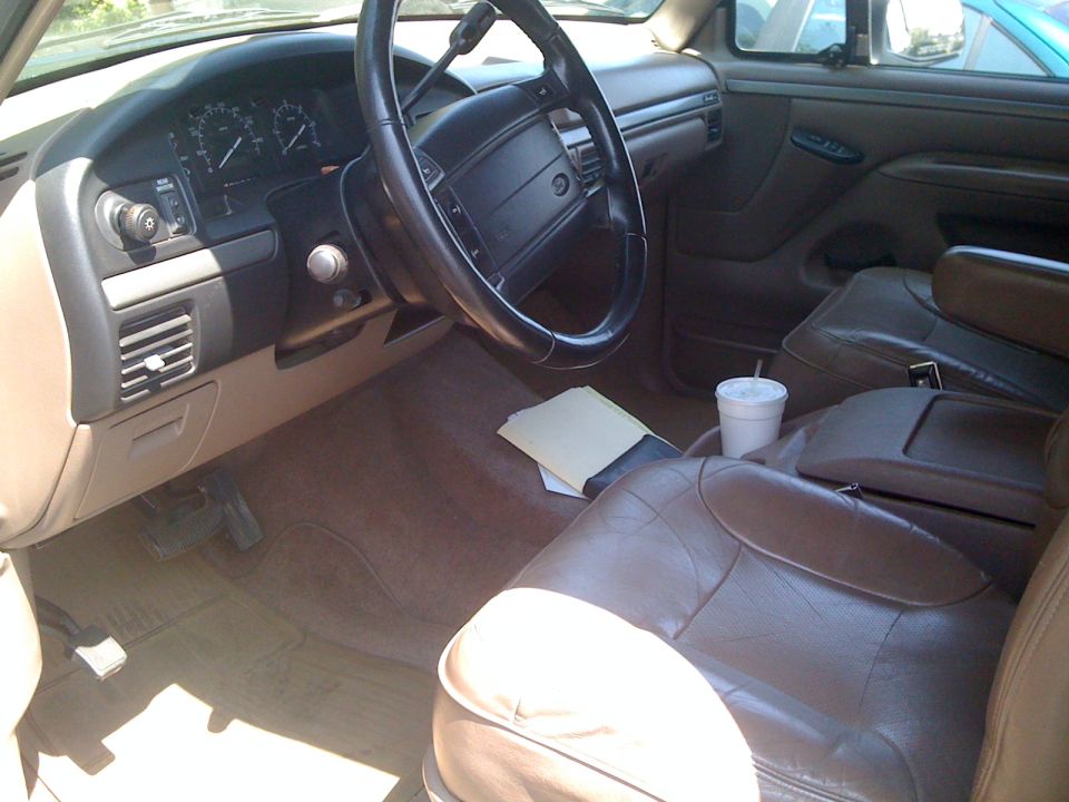 1995 Ford Bronco interior showing dashboard, steering wheel, brown leather seats, and center console