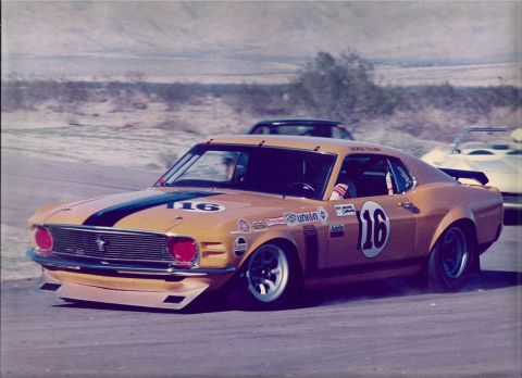 1973 Ford Mustang - A vintage race car speeds around a track, displaying sponsor decals and the number 16.