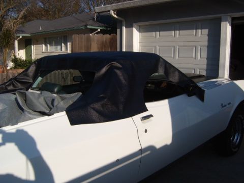 1973 Ford Ranchero - A white convertible car, possibly a 1970s model, is partially covered with a black top.