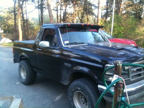 1993 Ford Bronco - A black Ford Bronco is parked outside with trees in the background and another vehicle visible.