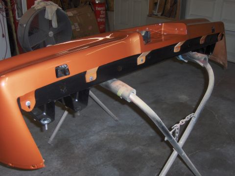 1980 Chevrolet Camaro - Car bumper assembly, painted orange, is shown on a stand in a garage or workshop.