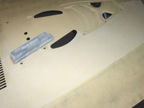 1980 Chevrolet Camaro - A beige car hood is shown with black trim pieces and a sanding block on its surface.