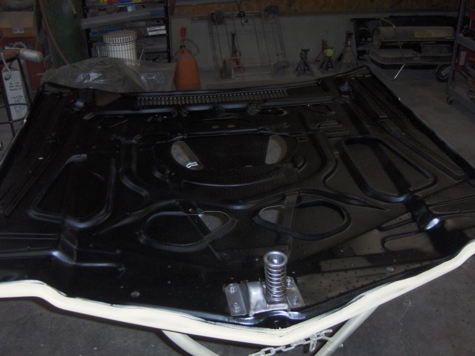 Underside of black car hood with springs and bracing