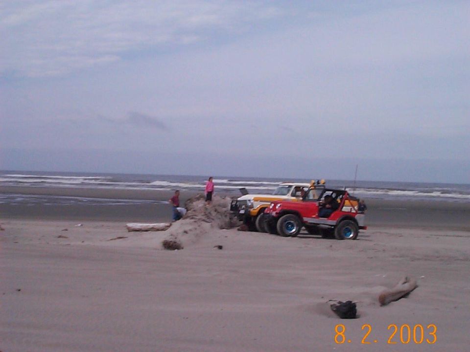 Red topless CJ 4x4 and a yellow and white Bronco parked on a beach