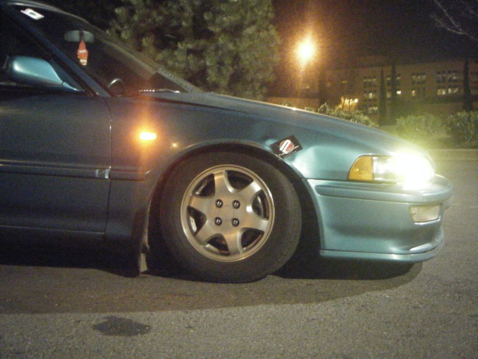 Teal sedan front fender and wheel, with a sticker on the fender