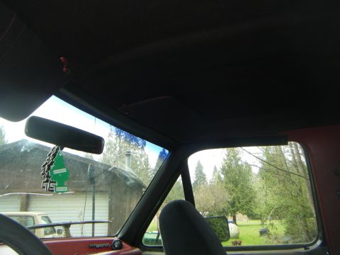 1990 Ford Bronco interior showing dashboard, rearview mirror with air freshener, and windshield view of a gar…