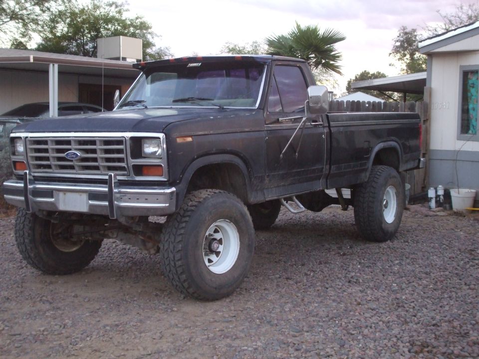 Black lifted Ford F-250 pickup truck parked on gravel, front quarter view