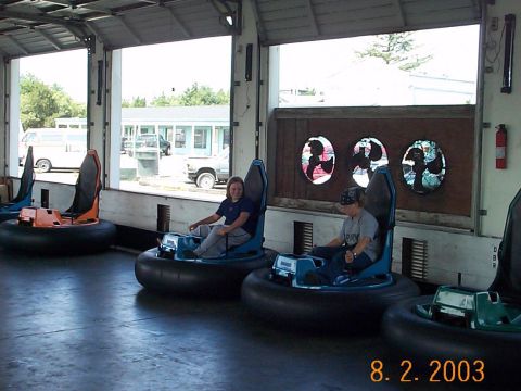 1983 Ford Bronco - Two people sit in bumper cars inside a garage, with other bumper cars visible.