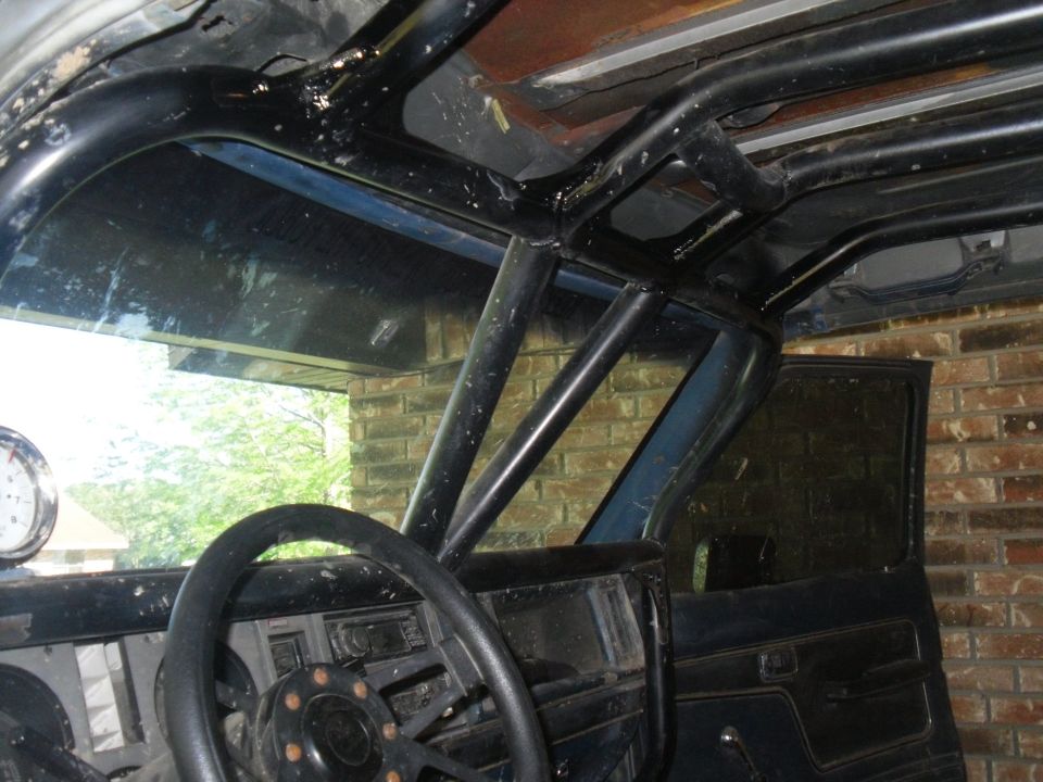 Interior view of a roll cage and dashboard with a gauge