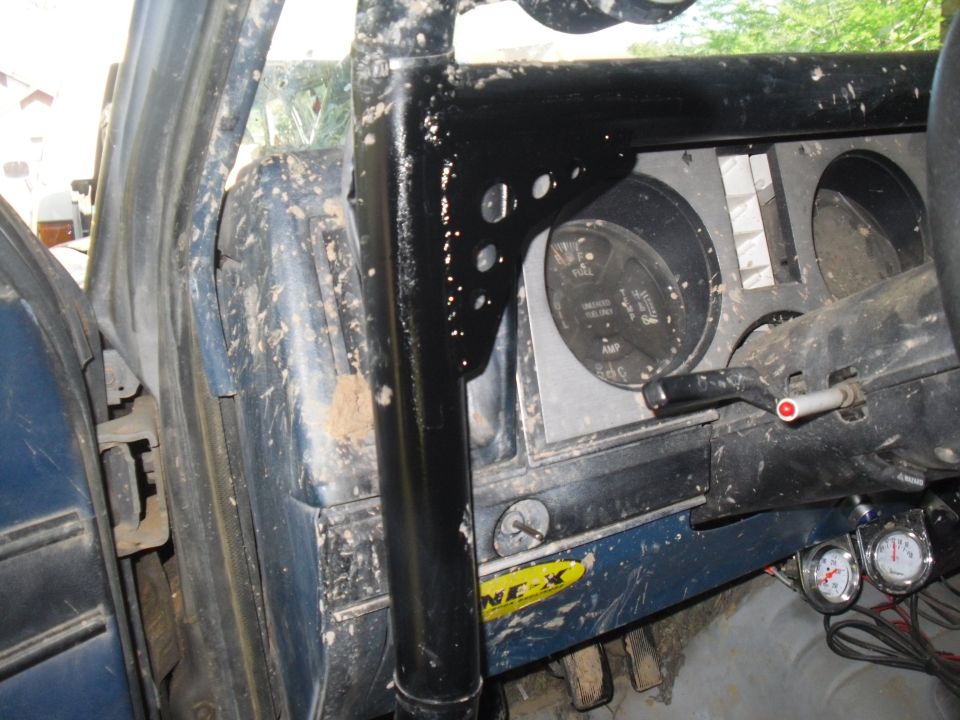 Interior of a 1984 Ford Bronco II with a black roll cage, muddy dashboard, and gauges