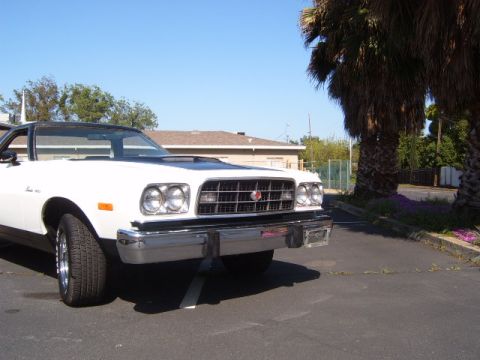 1973 Ford Ranchero - Front view of a white coupe utility with a black hood scoop and chrome bumper parked in a lot.