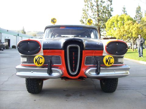 1990 Ford Bronco - Head-on view of a vintage Edsel race car showing its distinctive vertical center grille, orange and black body and yellow KC lights.