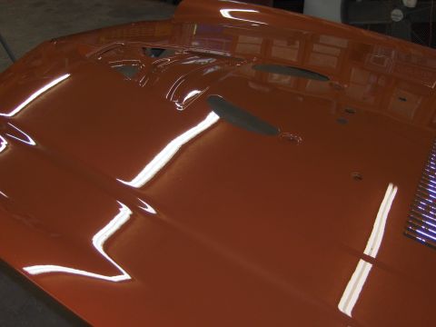 1980 Chevrolet Camaro - The hood of a car is shown from a high angle, painted in a glossy orange finish.