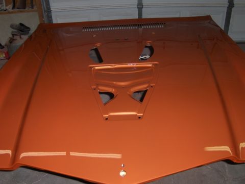 1980 Chevrolet Camaro - This orange hood features a distinctive scoop and ventilation slots, likely for a performance vehicle.