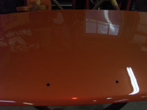 1980 Chevrolet Camaro - Close-up of an orange car hood, showing reflections and two small holes.