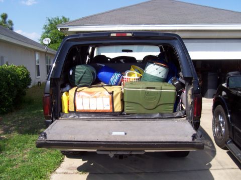 1994 Ford Bronco - This black Ford Bronco, likely from the early to mid-1990s, is packed for a trip with camping equipment visible in the cargo area.