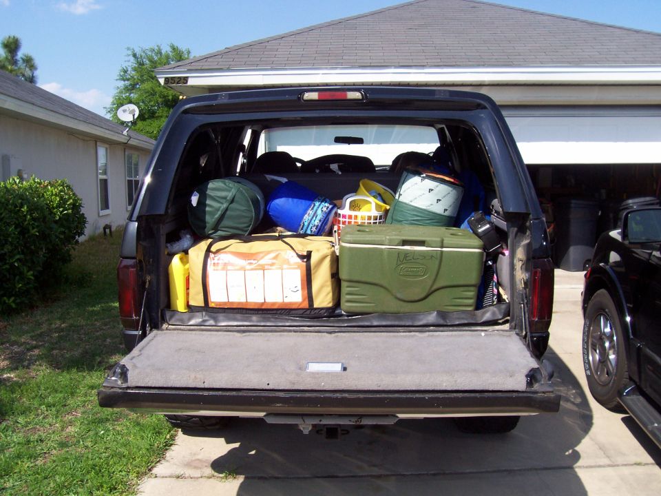 Black Ford Bronco rear view, tailgate open, packed with camping gear including coolers and bags