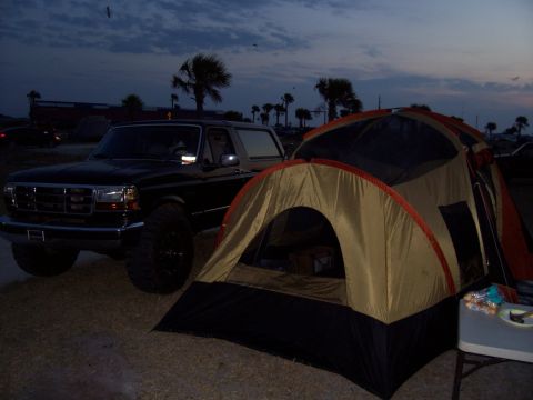 1994 Ford Bronco - A 1994 Ford Bronco is parked near a campsite with a tent set up as the sun sets.