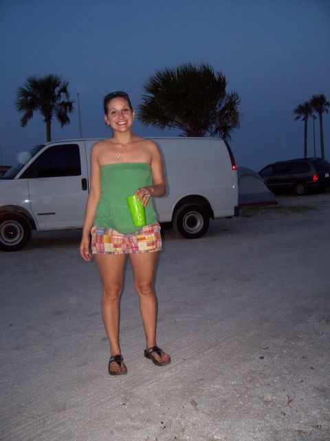 1994 Ford Bronco - A woman stands before a white van at dusk, with other vehicles and palm trees in the background.