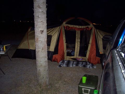 1994 Ford Bronco - A campsite is set up with a large tent and a vehicle parked beside it, illuminated by artificial light.