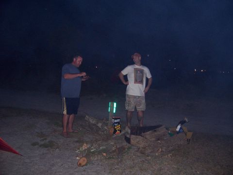 1994 Ford Bronco - Two men are gathered on a beach at night, with a fire pit and supplies visible.