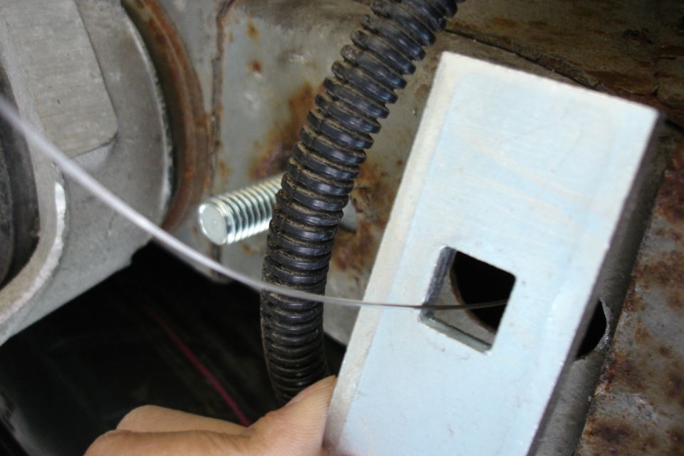 Hand routing black corrugated wiring loom through a white frame bracket with fish wire