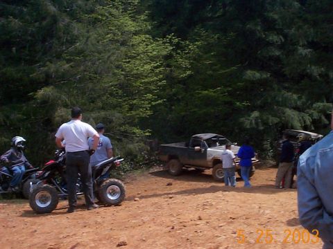 1983 Ford Bronco - A group of people stand around ATVs and a pickup truck in a wooded area.