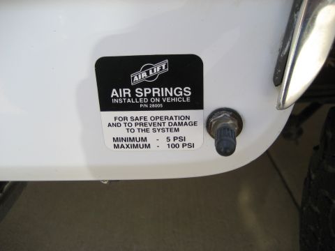 1993 Ford Bronco — White vehicle panel with an 'Air Lift Air Springs' sticker and a valve stem