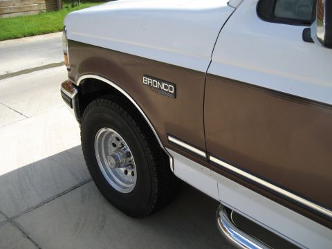 Side view of a 1993 Ford Bronco with a brown stripe and a Bronco badge