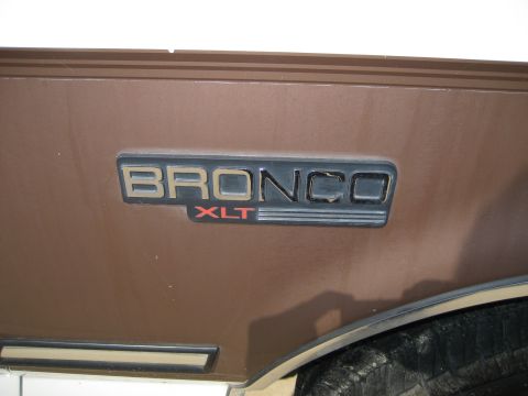 Close-up of a Bronco XLT emblem on a brown vehicle panel