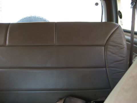 Brown perforated leather rear seat and spare tire visible through window of 1993 Ford Bronco