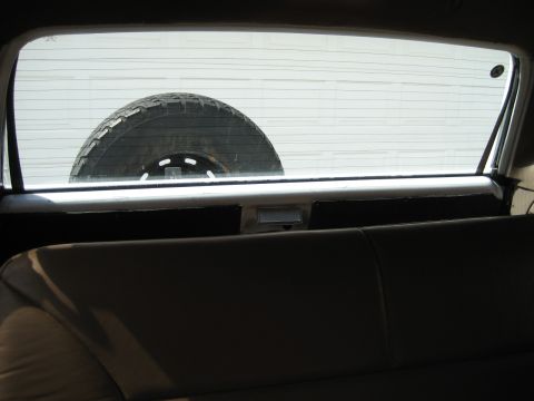 1993 Ford Bronco — Spare tire visible through the rear window of a vehicle. A white garage door is in the background