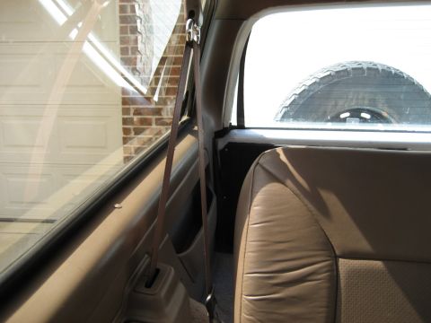 1993 Ford Bronco — Tan leather seat and spare tire visible through rear window of a vehicle
